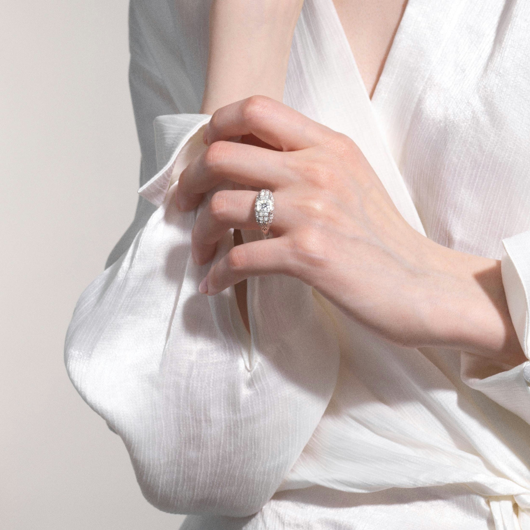 A woman in a white blouse with a diamond encrusted white-gold ring.