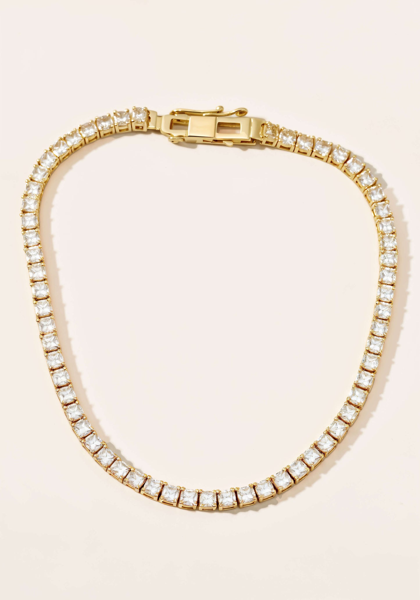 A gold tennis necklace, a continuous strand diamonds set in square links.
