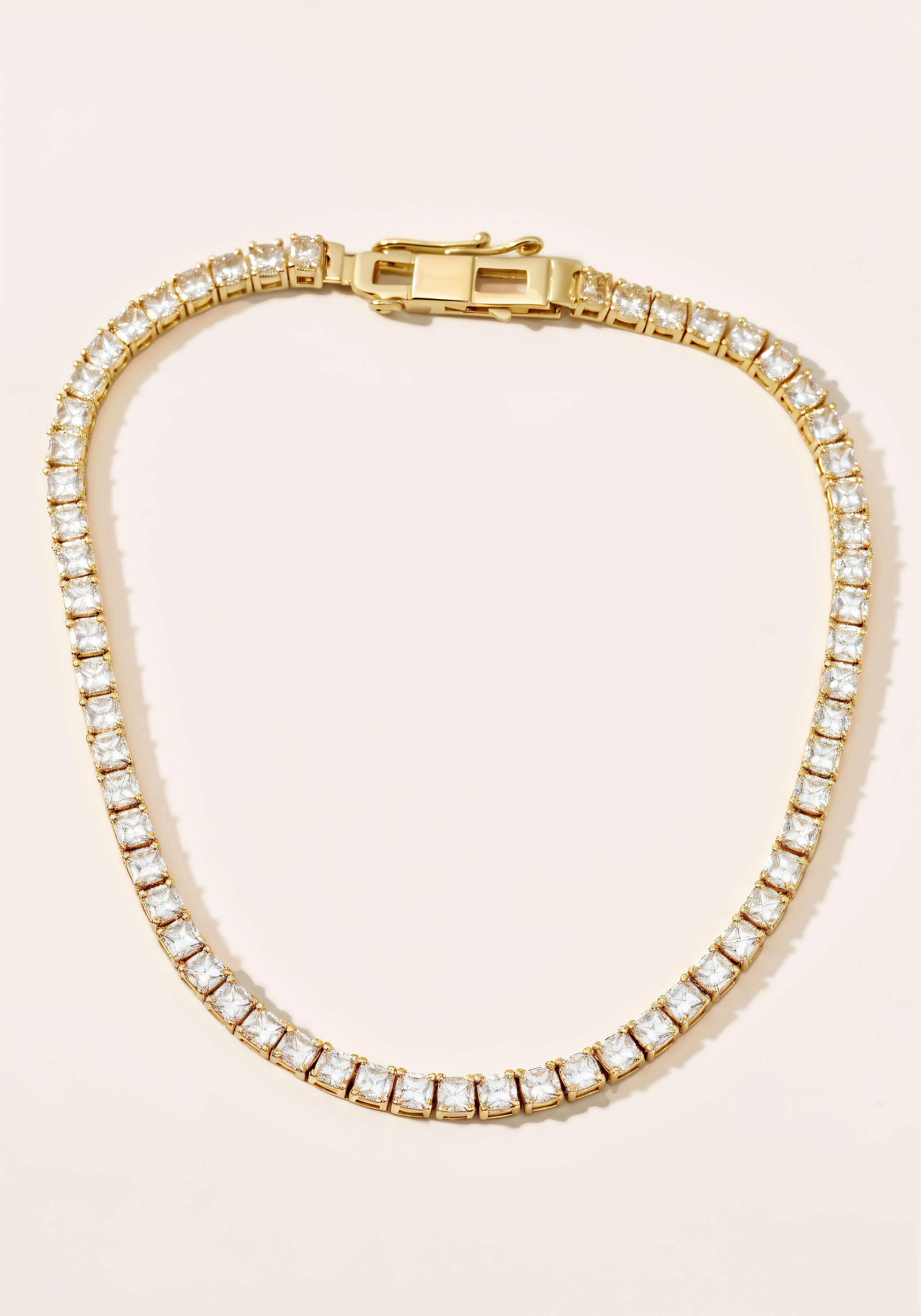 A gold tennis necklace, a continuous strand diamonds set in square links.