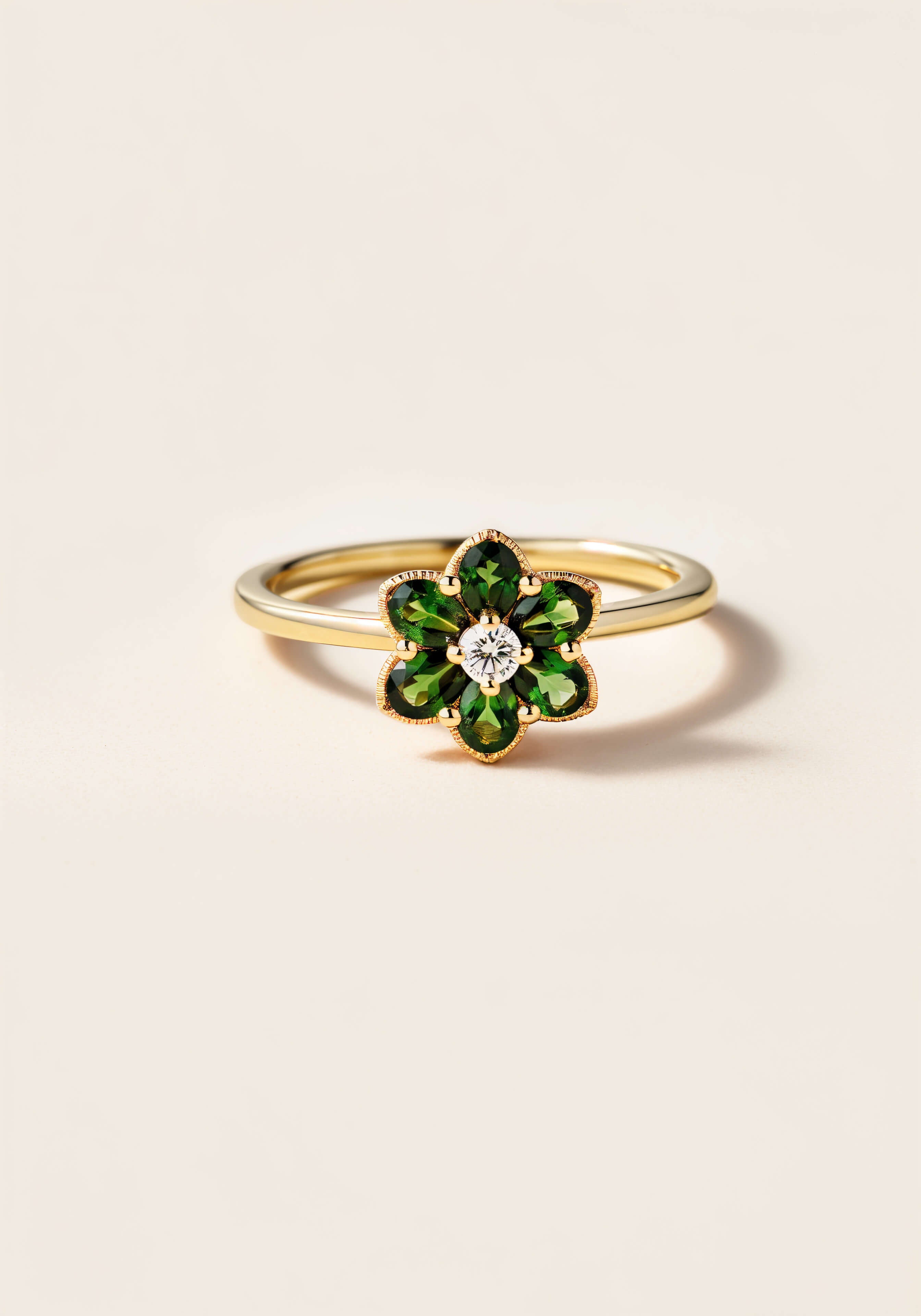 A smooth gold ring with a six-petaled flower made of emeralds and a diamond in the center.