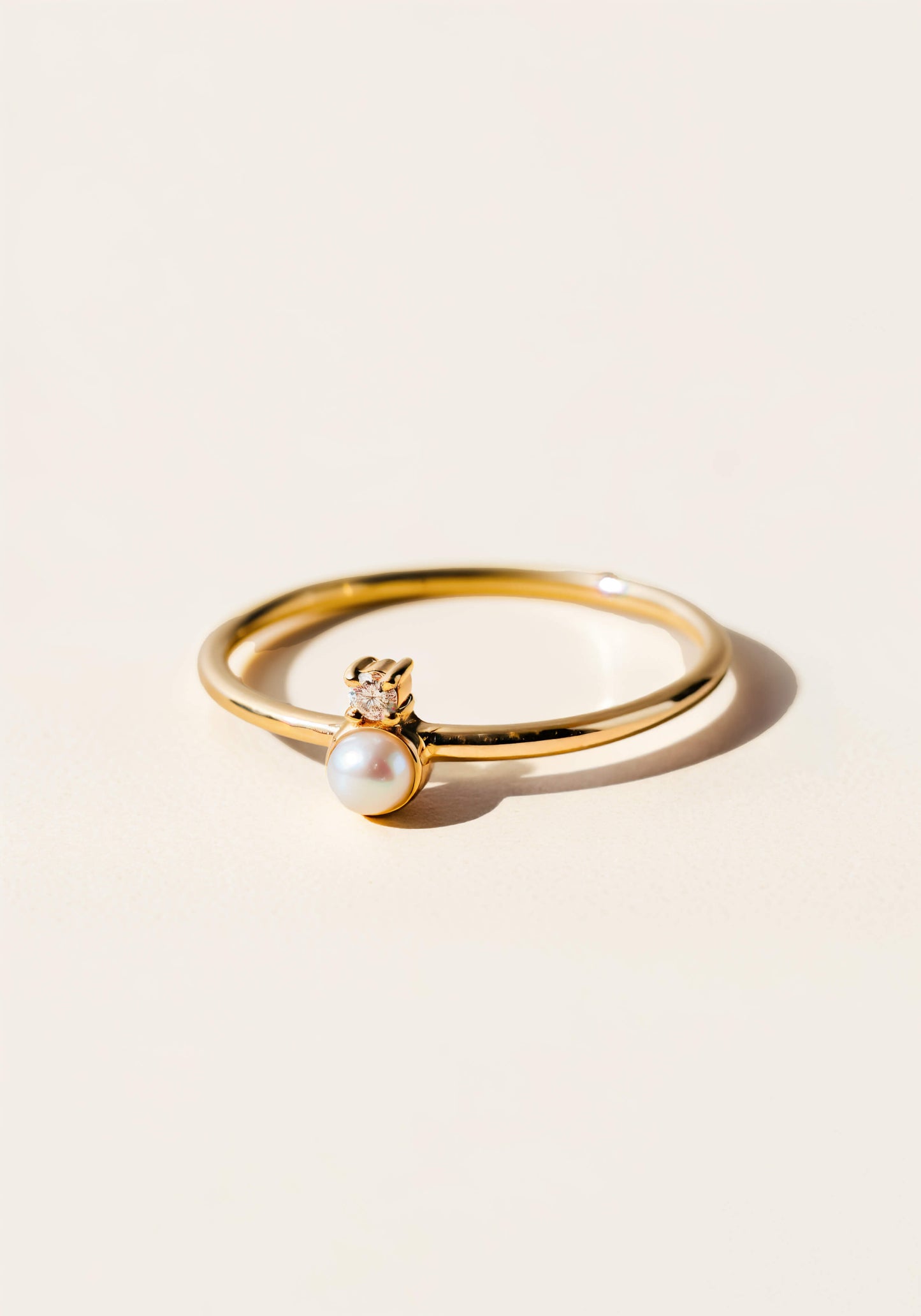 A white gold rign with a pearl and diamond set in the center.